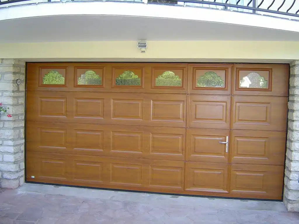 Porte de garage sectionnelle avec portillon intégré, finition aspect bois et panneaux à cassette, installation à Saint-Jeannet.