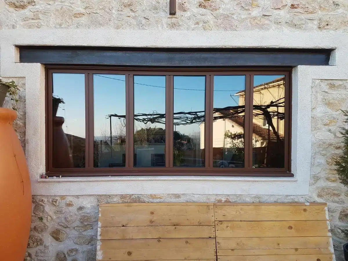 Fenêtre aluminium K-LINE style atelier couleur rouille installée sur façade en pierre à Grasse.