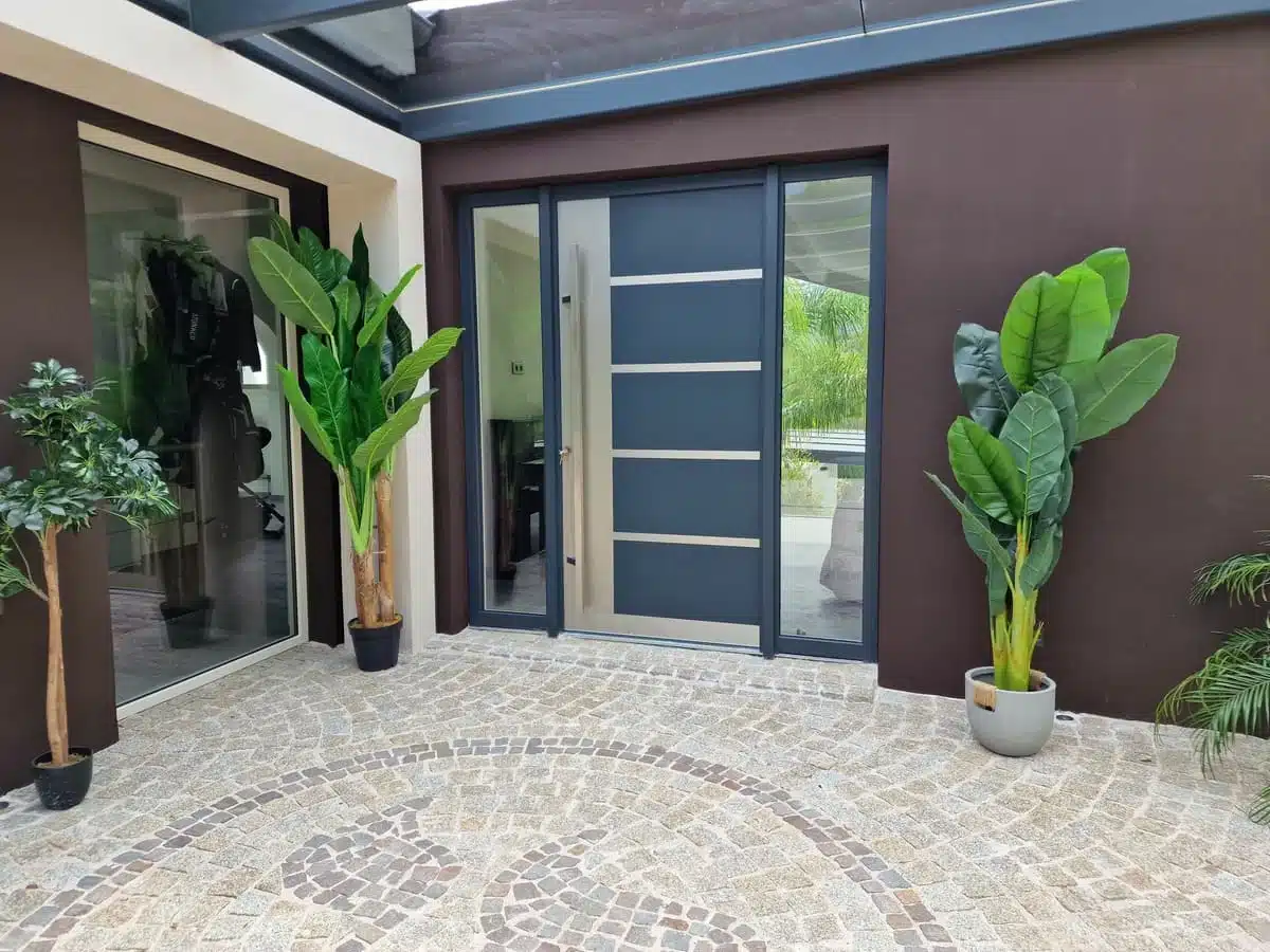 Porte d’entrée en aluminium Finstral installée à La Turbie, au design contemporain avec vitrage latéral et finitions gris anthracite