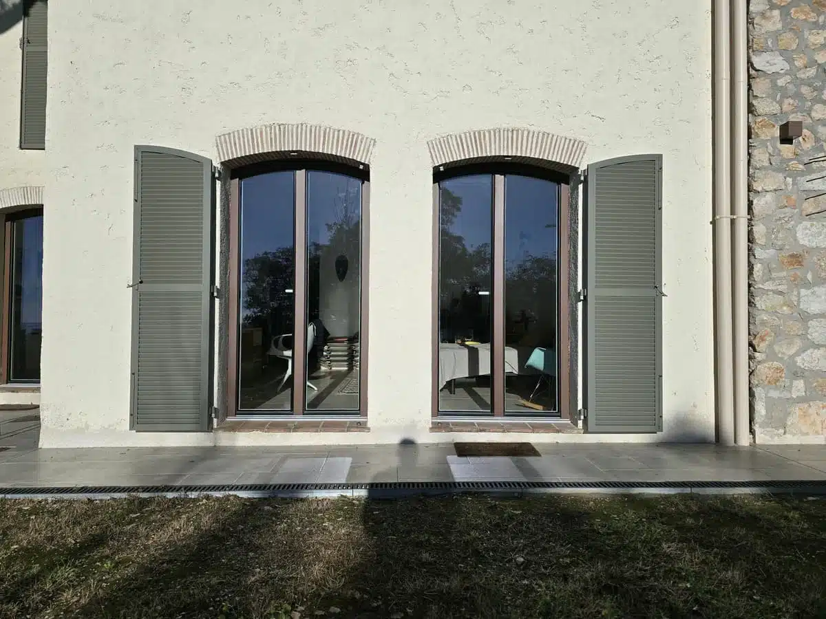 Fenêtres cintrées en PVC/Alu Finstral teinte Mars2525 avec persiennes aluminium EHRET, installées à Tourrettes-sur-Loup. Une alliance élégante entre performance, durabilité et charme architectural.