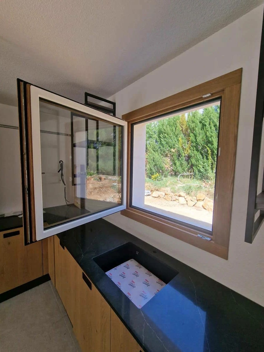 Fenêtre mixte bois/alu finition chêne de la marque Bildau & Bussman installée à Mouans-Sartoux. Une menuiserie haut de gamme alliant chaleur du bois et performance de l’aluminium, parfaitement intégrée à une cuisine contemporaine.