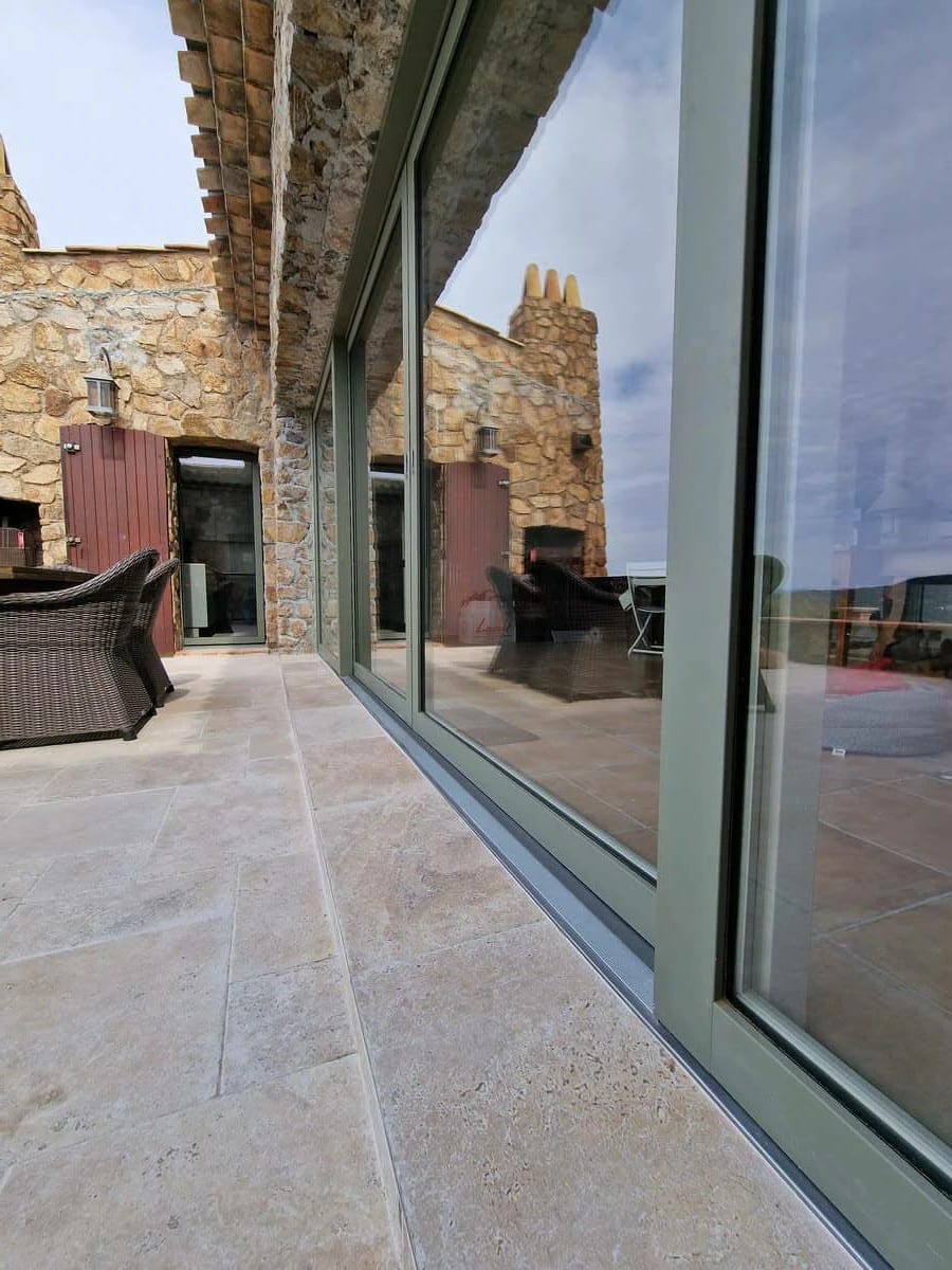 Baie vitrée coulissante à levage en aluminium Finstral, finition RAL 7003, installée à Agay. Une menuiserie haut de gamme offrant luminosité, isolation et esthétisme contemporain, parfaitement intégrée à une façade en pierre naturelle.