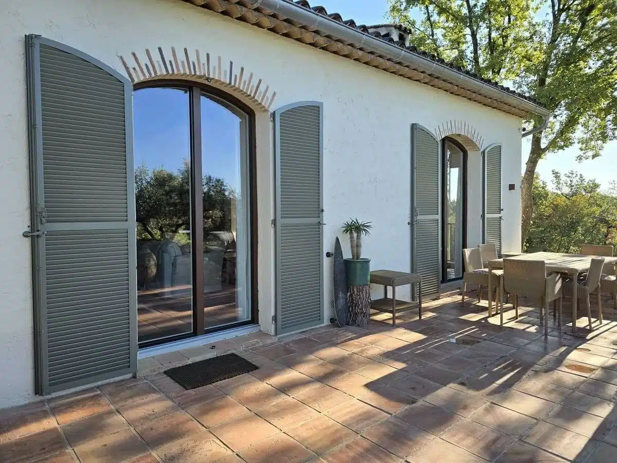 Porte-fenêtres cintrées en aluminium Finstral avec volets battants Ehret installées à Tourrettes-sur-Loup sur façade provençale lumineuse