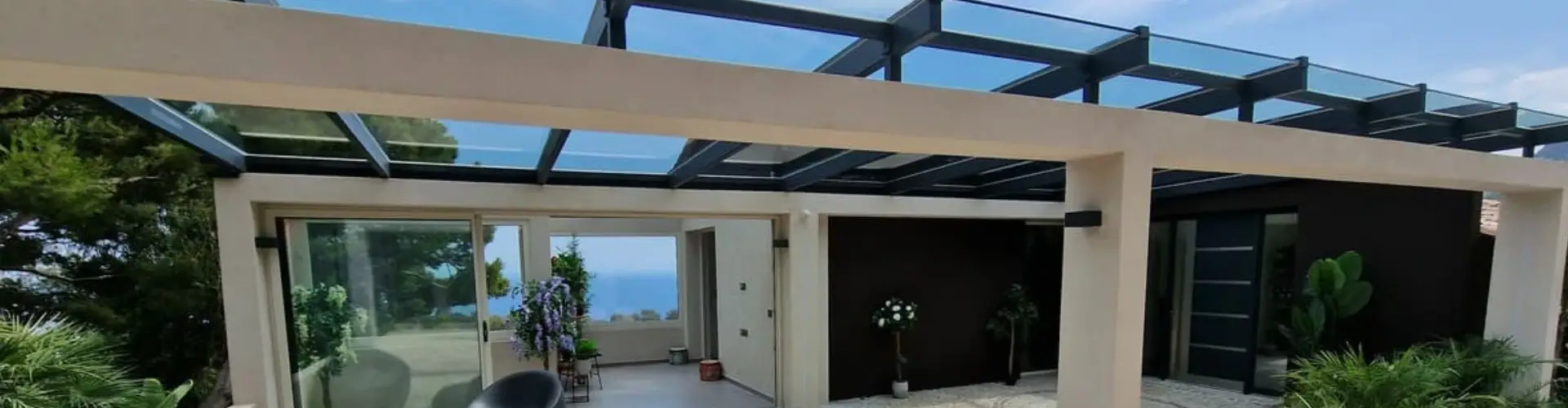 Véranda contemporaine avec avancée vitrée et baies coulissantes Technal à La Turbie. Une réalisation design et lumineuse offrant une vue panoramique sur la mer, alliant confort, modernité et élégance architecturale.