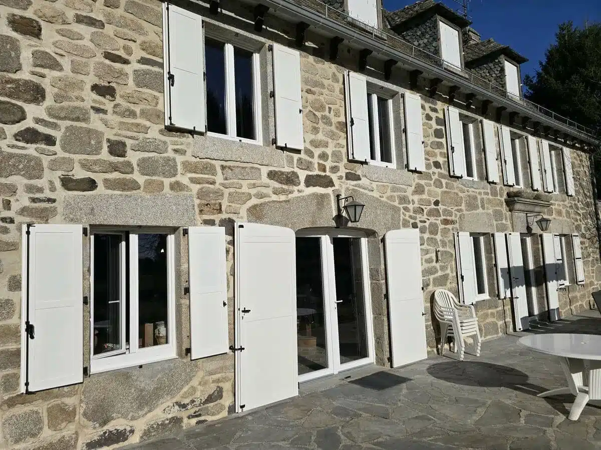 Volets battants aluminium isolés EHRET avec panneaux pleins installés sur maison en pierre dans l’Aubrac.